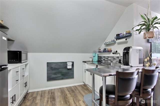 bar featuring white cabinetry, stainless steel fridge, decorative backsplash, dark wood-type flooring, and sink