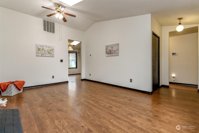 unfurnished living room featuring lofted ceiling, ceiling fan, a textured ceiling, and hardwood / wood-style floors