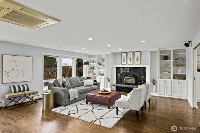 living room featuring built in shelves, recessed lighting, a high end fireplace, and wood finished floors