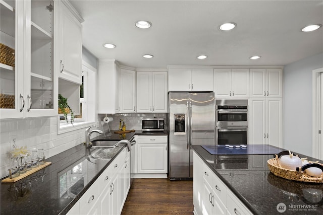 kitchen featuring white cabinets, glass insert cabinets, dark wood-type flooring, stainless steel appliances, and backsplash