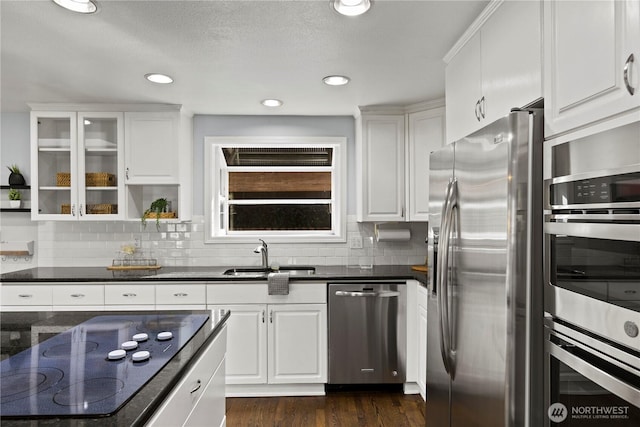 kitchen with stainless steel appliances, dark wood-style flooring, white cabinets, and a sink