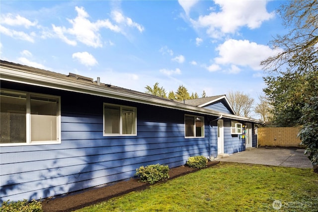 view of side of home with fence, a lawn, and a patio