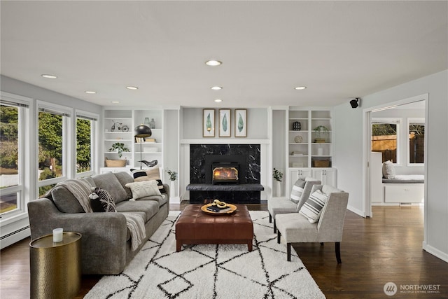 living area featuring baseboards, wood finished floors, built in shelves, a fireplace, and recessed lighting