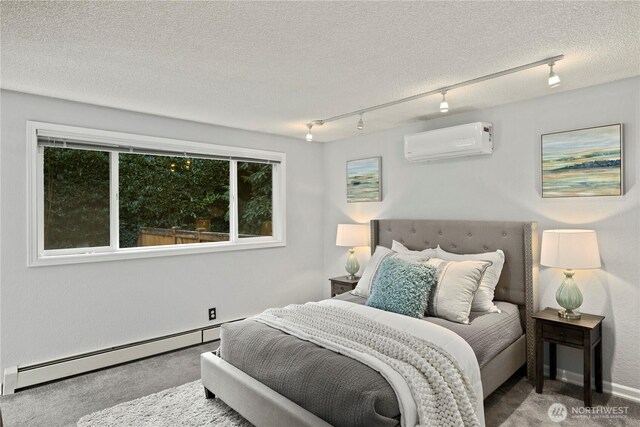 bedroom with baseboard heating, a wall mounted AC, carpet flooring, a textured ceiling, and track lighting