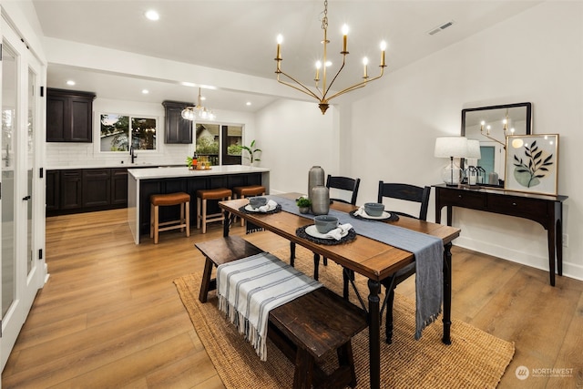 dining room featuring sink, light hardwood / wood-style flooring, and a notable chandelier