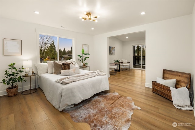 bedroom with access to outside, a notable chandelier, multiple windows, and light hardwood / wood-style flooring