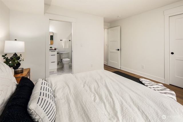 bedroom with ensuite bathroom and dark hardwood / wood-style flooring