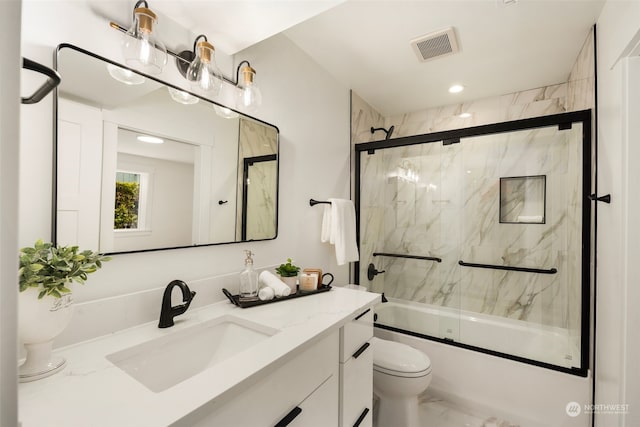 full bathroom featuring toilet, vanity, and shower / bath combination with glass door