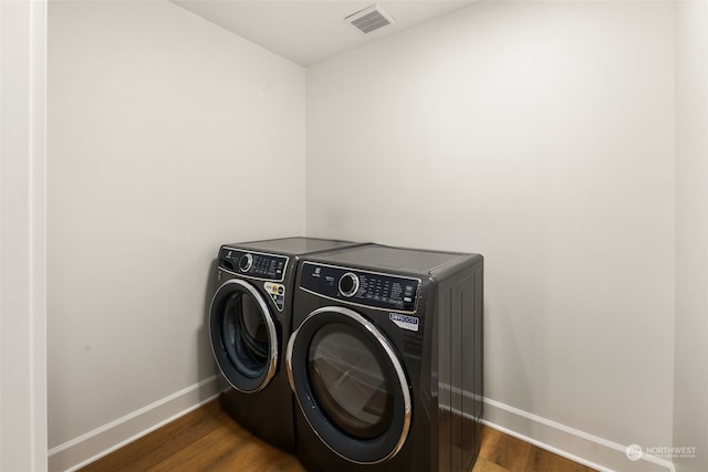 laundry area with dark hardwood / wood-style flooring and independent washer and dryer