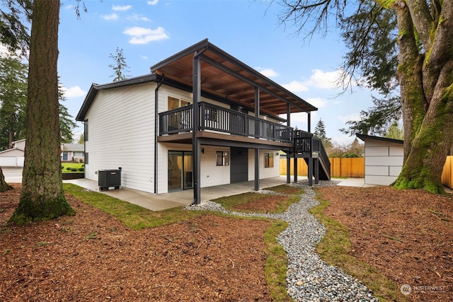 rear view of property featuring central AC unit, a deck, and a patio