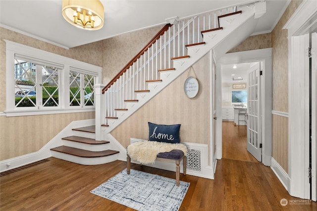 stairway with a chandelier, crown molding, and hardwood / wood-style flooring