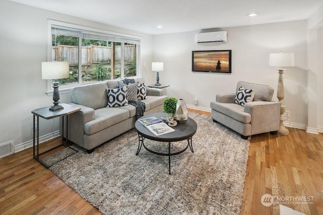 living room with hardwood / wood-style floors and a wall unit AC