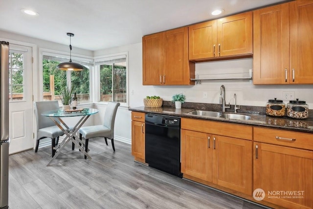 kitchen featuring pendant lighting, black dishwasher, dark stone countertops, sink, and light hardwood / wood-style flooring