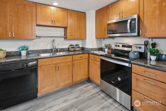 kitchen with sink, dark stone countertops, stainless steel appliances, and light hardwood / wood-style floors