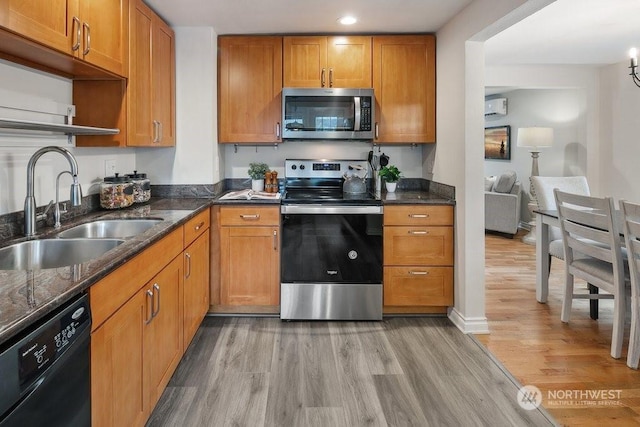 kitchen with light hardwood / wood-style floors, sink, appliances with stainless steel finishes, and an AC wall unit