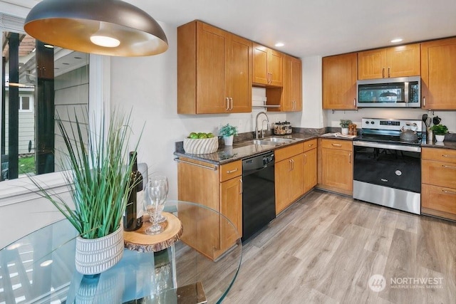 kitchen with light hardwood / wood-style floors, sink, appliances with stainless steel finishes, and dark stone countertops