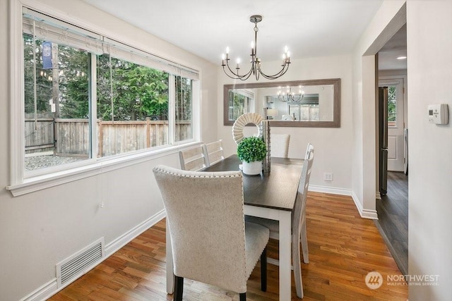 dining area featuring wood-type flooring and an inviting chandelier