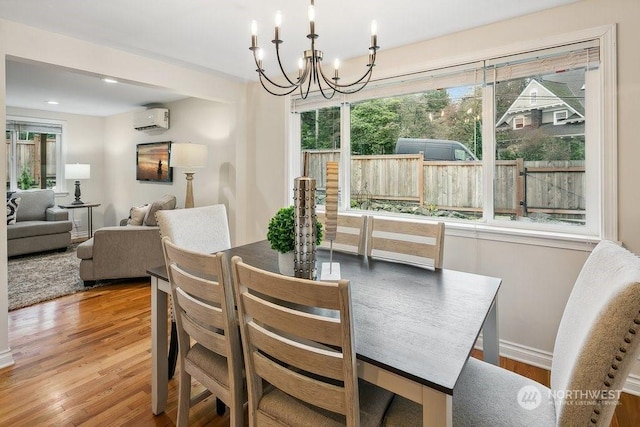 dining area with a healthy amount of sunlight, a wall mounted air conditioner, and hardwood / wood-style flooring