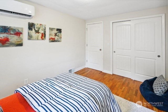 bedroom featuring hardwood / wood-style flooring, a closet, and a wall mounted air conditioner