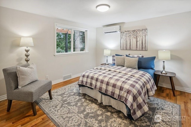 bedroom with hardwood / wood-style flooring and a wall mounted air conditioner