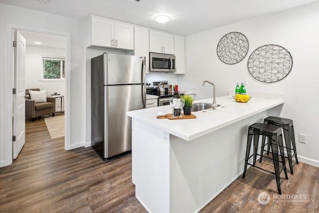 kitchen featuring appliances with stainless steel finishes, white cabinets, kitchen peninsula, and sink