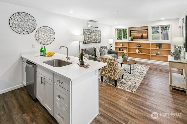 kitchen featuring stainless steel dishwasher, kitchen peninsula, sink, dark wood-type flooring, and white cabinets