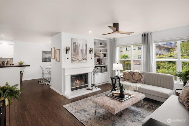 living room with ceiling fan, built in features, dark hardwood / wood-style floors, and sink