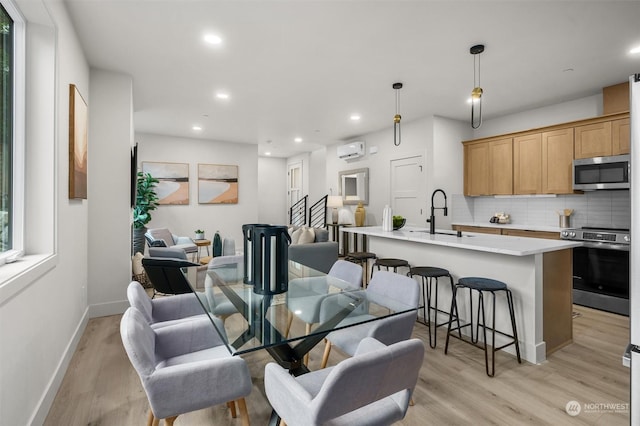 dining space with light hardwood / wood-style flooring, sink, and a wall mounted air conditioner