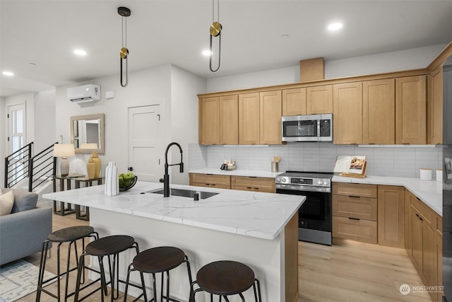 kitchen featuring backsplash, pendant lighting, sink, an island with sink, and stainless steel appliances