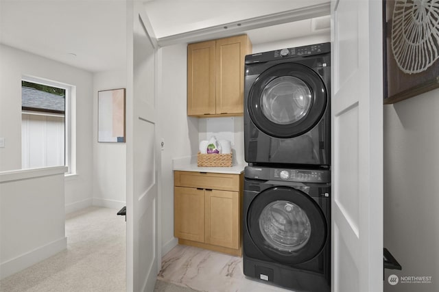 laundry area with cabinets and stacked washer and dryer