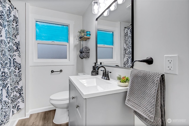 bathroom with toilet, wood-type flooring, plenty of natural light, and vanity