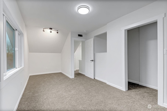 bonus room with lofted ceiling and light colored carpet