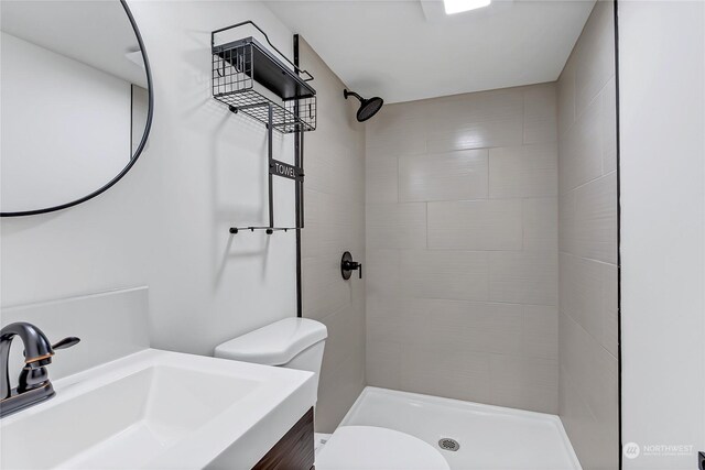 bathroom with toilet, vanity, and a tile shower