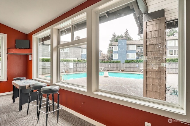 doorway to outside featuring lofted ceiling and carpet