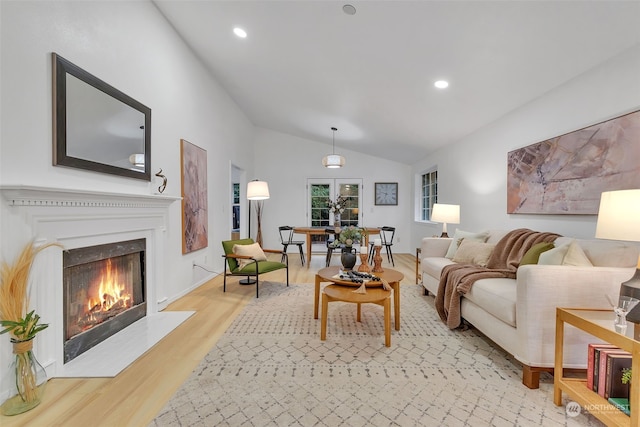 living room with light wood-type flooring, lofted ceiling, and french doors