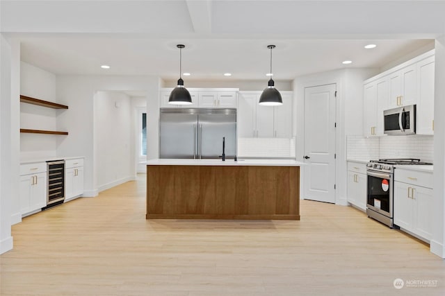 kitchen with white cabinetry, wine cooler, hanging light fixtures, a kitchen island with sink, and stainless steel appliances