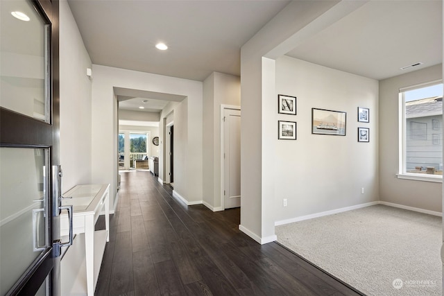 corridor with a wealth of natural light and dark hardwood / wood-style flooring