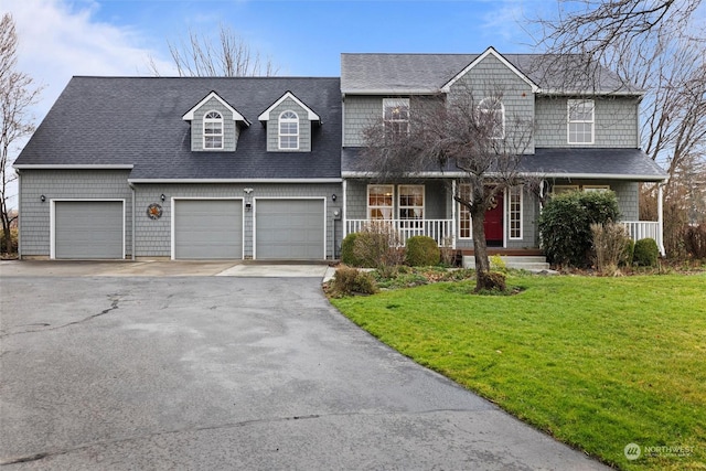 view of front of property with covered porch, a front yard, and a garage