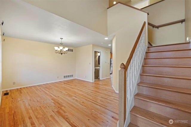 staircase with hardwood / wood-style flooring, a high ceiling, and an inviting chandelier