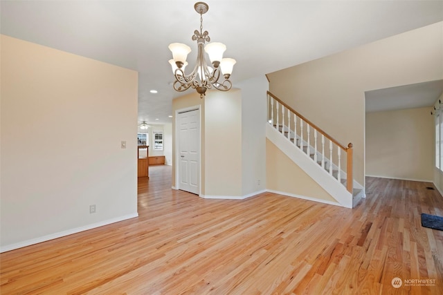 spare room featuring a chandelier and light wood-type flooring