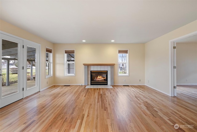 unfurnished living room featuring light wood-type flooring and a tile fireplace