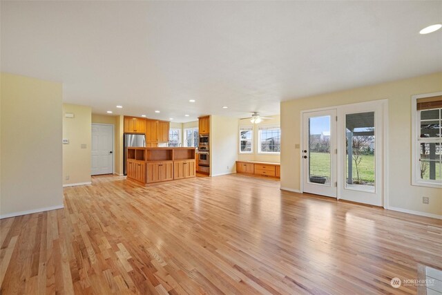 unfurnished living room featuring ceiling fan, a healthy amount of sunlight, and light hardwood / wood-style floors