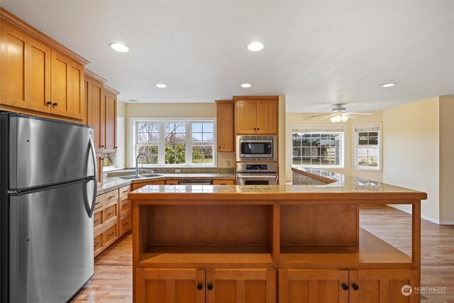 kitchen featuring a center island, stainless steel appliances, sink, ceiling fan, and light hardwood / wood-style flooring