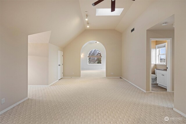 hallway with light colored carpet and vaulted ceiling with skylight