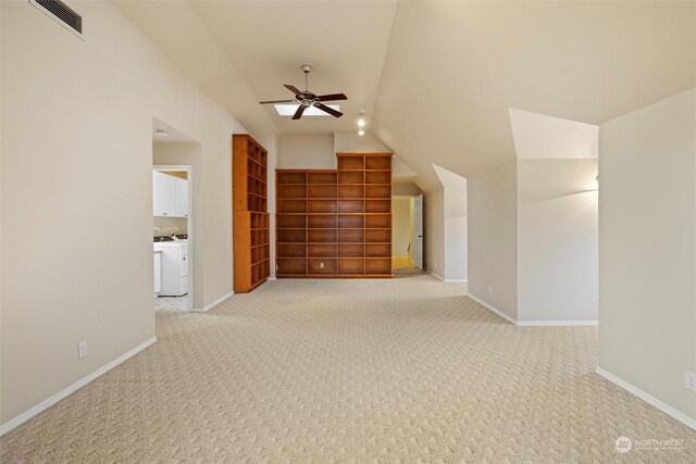 interior space with ceiling fan, light colored carpet, washer / clothes dryer, and vaulted ceiling