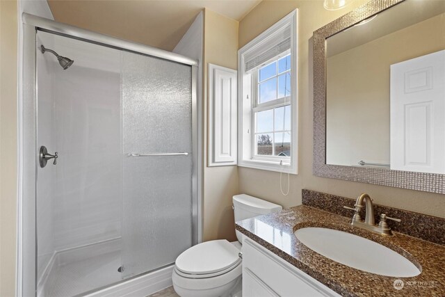 bathroom with a shower with shower door, toilet, and vanity