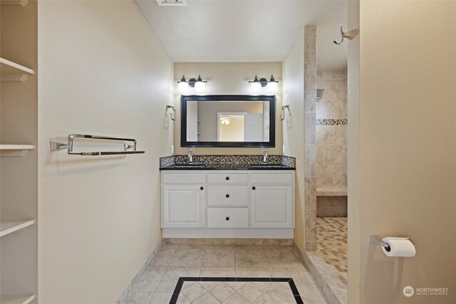 bathroom with vanity, a tile shower, and tile patterned flooring