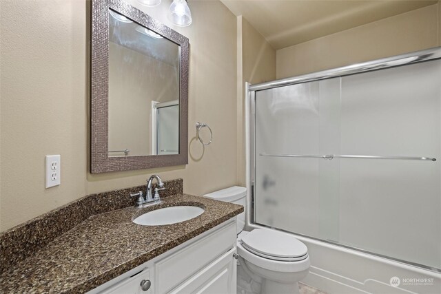 full bathroom featuring bath / shower combo with glass door, toilet, and vanity