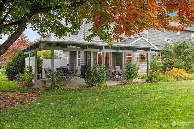 rear view of house featuring a lawn and a patio