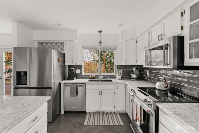 kitchen with backsplash, sink, white cabinetry, hanging light fixtures, and appliances with stainless steel finishes